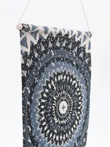 Tapiz decorativo de pared con diseño circular de estilo mandala en tonos azules y blancos. Incluye flecos en la parte inferior y un cordón para colgar.