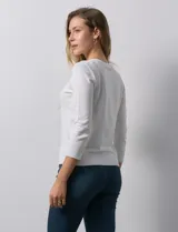 Cardigan blanco de tejido fino con abertura central y botones.