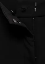 Pantalon de vestir de corte recto y tiro medio, con bolsillos laterales y cierre oculto. Presenta un diseño clásico con trabillas para cinturón y forro interior.