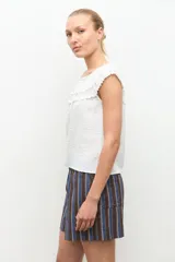 Blusa negra estilo bardot con escote de hombros descubiertos, detalles de volados fruncidos en el pecho y diseño sin mangas.