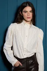 Camisa de algodón con estampado de rayas verticales finas, cuello alto con detalle de encaje broderie, cierre frontal con botones y mangas con frunces en los hombros y detalles de encaje.