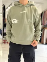 Canguro oversize gris con capucha y gran estampado gráfico trasero en tono más oscuro.