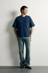 Jeans flare fit de denim rígido en color azul con efecto lavado. Presentan tiro medio, diseño de cinco bolsillos y cierre frontal con cremallera y botón.