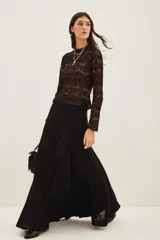 Falda larga de punto en color negro, con diseño plisado y acabado con sutil brillo metalizado. Presenta un corte acampanado con caída fluida.