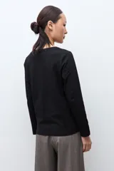 Remera de manga larga en color blanco, con cuello redondo y detalle de botones en los puños.