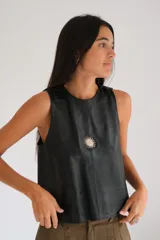 Chaleco negro de gamuza con cuello redondo, sin mangas y un bordado de sol en el pecho.