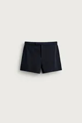 Shorts de corte retro confeccionados en tejido de piqué elástico, de color azul marino, con bolsillos frontales y cierre cruzado en el delantero con cremallera y gancho metálico oculto.