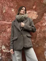 Blazer de lana en tono marrón con textura tejida, corte estructurado, solapas clásicas, cierre frontal de un botón y bolsillos laterales con solapa.