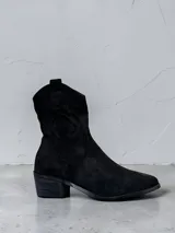 Bota estilo texana de caña media, confeccionada en material tipo gamuza color negro. Presenta costuras decorativas en la caña y un taco cuadrado de altura media.