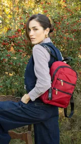 Mochila rosa de tafeta con apertura superior con cierre y tiradores metálicos, bolsillos internos, bolsillo con doble cierre metálico al frente, asas rígidas de mano y correas regulables para colgar en la espalda.