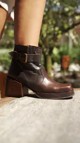 Botas cortas de cuero color marrón oscuro con hebillas y estribo desmontable.