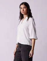 Blusa de gasa estampada en tonos azules y negros, marca Sioni. Tiene cuello a la base con escote en V, abertura central con botones y mangas tres cuartos fruncidas.