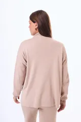 Buzo tejido de punto color negro, con cuello alto, manga larga y corte holgado con aberturas laterales en el ruedo.