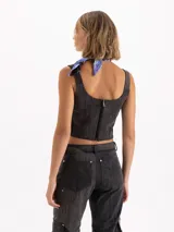 Top de gabardina con efecto batik, corte ajustado al cuerpo y largo hasta la cintura. Presenta escote cuadrado con detalle de volados en cuero vacuno, breteles anchos y apliques de remaches metálicos en forma de flor en el frente.