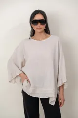 Blusa de lino color verde militar, holgada, de manga 3/4 con volados en los puños, cuello redondo y detalle de alforzas horizontales en el dobladillo.