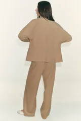 Chaqueta color tostado con cuello solapa, manga larga y cierre frontal con cremallera. Presenta bolsillos delanteros de plastrón con solapa y detalle de cintura ajustable con lazada.