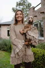 Sweater de lana merino color beige, con silueta amplia y relajada. Presenta mangas con volumen, terminaciones con volados de lino y flecos decorativos en el ruedo y las mangas.