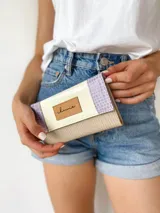 Billetera de cuero color crema, lila y beige con cierre de broche y monedero externo.