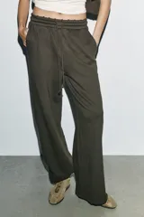 Pantalón de tiro medio con pierna ancha, confeccionado en tejido lavado. Presenta cintura elástica ajustable con cordones, bolsillos laterales y bolsillos traseros decorados con estrellas y aplicaciones de tachas. El diseño cuenta con terminaciones desflecadas en el ruedo.