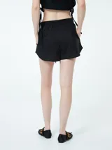 Conjunto compuesto por una camisa de manga larga con botones frontales y un short con cintura elástica y cordón ajustable, ambos en color negro.