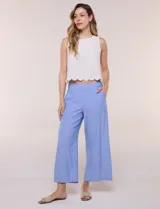 Pantalón crop de lino y rayón, con diseño wide leg de corte holgado, estampado tropical de hojas en tonos verde, azul y marrón sobre fondo blanco. Cuenta con pretina trasera elastizada y bolsillos delanteros.