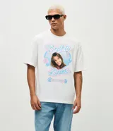 Remera de algodón con corte boxy, cuello redondo y mangas cortas. Presenta una estampa frontal con la imagen de Britney Spears rodeada por un corazón azul y gráficos decorativos en tonos rosados y celestes.