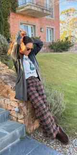 Pantalón de viyela a cuadros en tonos marrón y negro, de corte ancho y recto. Tiene botón en la pretina delantera y elástico en la parte trasera de la cintura.