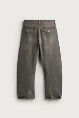 Jeans loose fit de hombre en denim de algodón color gris oscuro con efecto lavado. Presenta perneras con costuras giradas hacia los tobillos, tiro medio, cierre frontal con botones y bolsillos frontales con bolsillo cerillero.