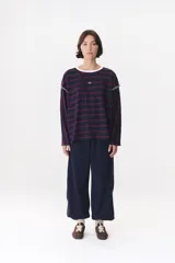 Remera de manga larga con corte oversized, color azul marino con cuello redondo en contraste color marrón. Presenta costuras decorativas a contratono hechas a mano en la zona de los hombros y logo bordado en el centro del pecho.