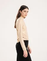 Polera dorada de cuello alto y manga larga, confeccionada en tejido elastizado con terminación metalizada.