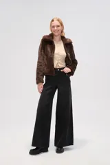 Chaqueta corta de piel sintética en color negro, con cuello clásico, cierre frontal con cremallera y mangas largas.