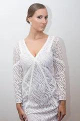 Vestido blanco de tul bordado con hilo de seda y cintas, con escote en V y mangas largas.