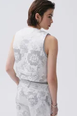 Chaleco de brocato blanco con diseño de flores plateadas, calce entallado y botones ocultos en el frente.