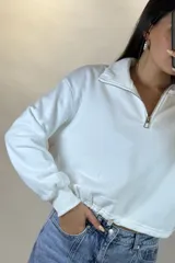 Buzo deportivo color blanco con cuello polo y cierre frontal parcial. Presenta mangas largas con puños elásticos y ruedo ajustable con cordón elástico.