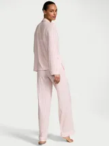 Pijama largo de modal suave con diseño de rayas verticales en tonos rosado y blanco, compuesto por una camisa de manga larga con botones al frente y bolsillo en el pecho, y un pantalón con cintura elástica y cordón ajustable.