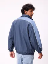 Campera rompevientos Rusty de nylon, color azul con detalles en azul claro en las mangas. Presenta cierre frontal, cuello alto y puños elásticos.