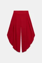 Pantalón fluido de tiro alto en color blanco, con pinzas delanteras, cintura elástica en la espalda y perneras anchas con aberturas laterales pronunciadas.