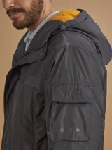 Campera de abrigo azul marino con capucha, cierre frontal con botones y cremallera, múltiples bolsillos y forro interior naranja.