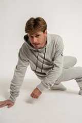 Canguro gris con capucha y cordones negros, bolsillos frontales y puños y cintura acanalados.