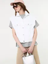 Chaleco blanco de jean con botones metálicos y sisas desflecadas.