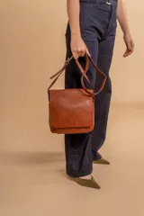 Bandolera de diseño simple con tapa frontal, confeccionada en material símil cuero. Cuenta con correa ajustable, división interna y bolsillos internos para mayor organización.