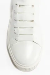 Zapatillas deportivas blancas con cuello acolchado, cierre de cordones y suela gruesa de goma con textura acanalada.