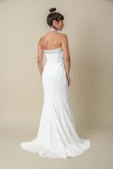 Vestido largo blanco de crepé, corte sirena, palabra de honor con bordado de piedras en el escote y cola pequeña.