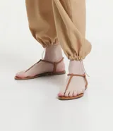 Sandalias planas Satinato de color beige, con diseño minimalista de tiras finas estilo thong y elástico en el talón.
