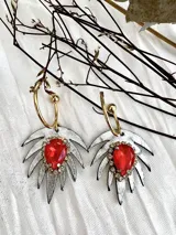 Aros colgantes con gancho dorado y dije con forma de hoja plateada con centro de piedra roja.