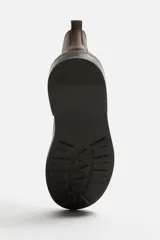 Bota tipo Chelsea de piel color marrón oscuro, con paneles elásticos laterales, tirador trasero y suela de goma con ligero tacón.