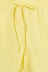 Shorts de tiro bajo color amarillo claro, confeccionado en tejido con lino. Presenta cintura elástica ajustable con cordones y aberturas laterales en el bajo.