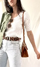 Cartera morada acolchada con diseño de rombos y asa de cadena gruesa.