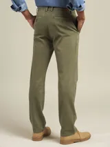 Pantalón de vestir color beige, de corte recto, con bolsillos laterales y traseros. Se ajusta a la cintura con cinturón de cuero marrón.