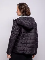 Campera capitoneada color ladrillo con capucha, cierre frontal con botones a presión y cremallera, bolsillos laterales y puños elastizados.